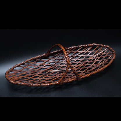 Signed madake elliptical bamboo basket side view showing forking overhead handle