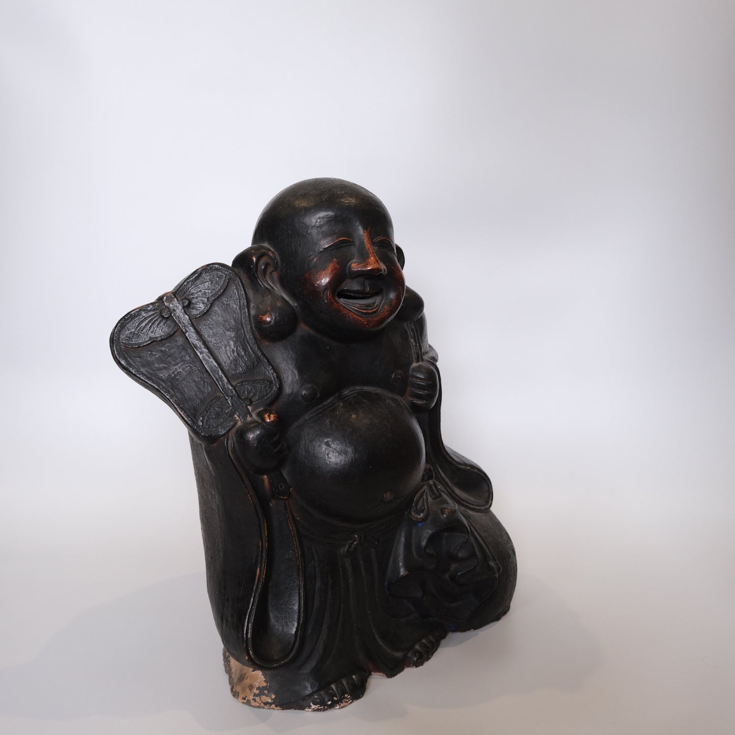 Large Hotei ceramic figure side view showing laughing expression and belly