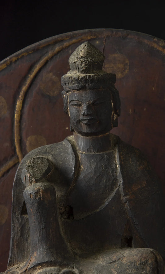 Carved wood folk bodhisattva seated in royal ease before a red and gold aureole on a lotus base, view 1 of 5